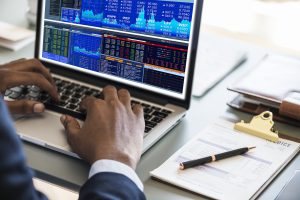 A business consultant looking at charts and spreadsheets on a laptop